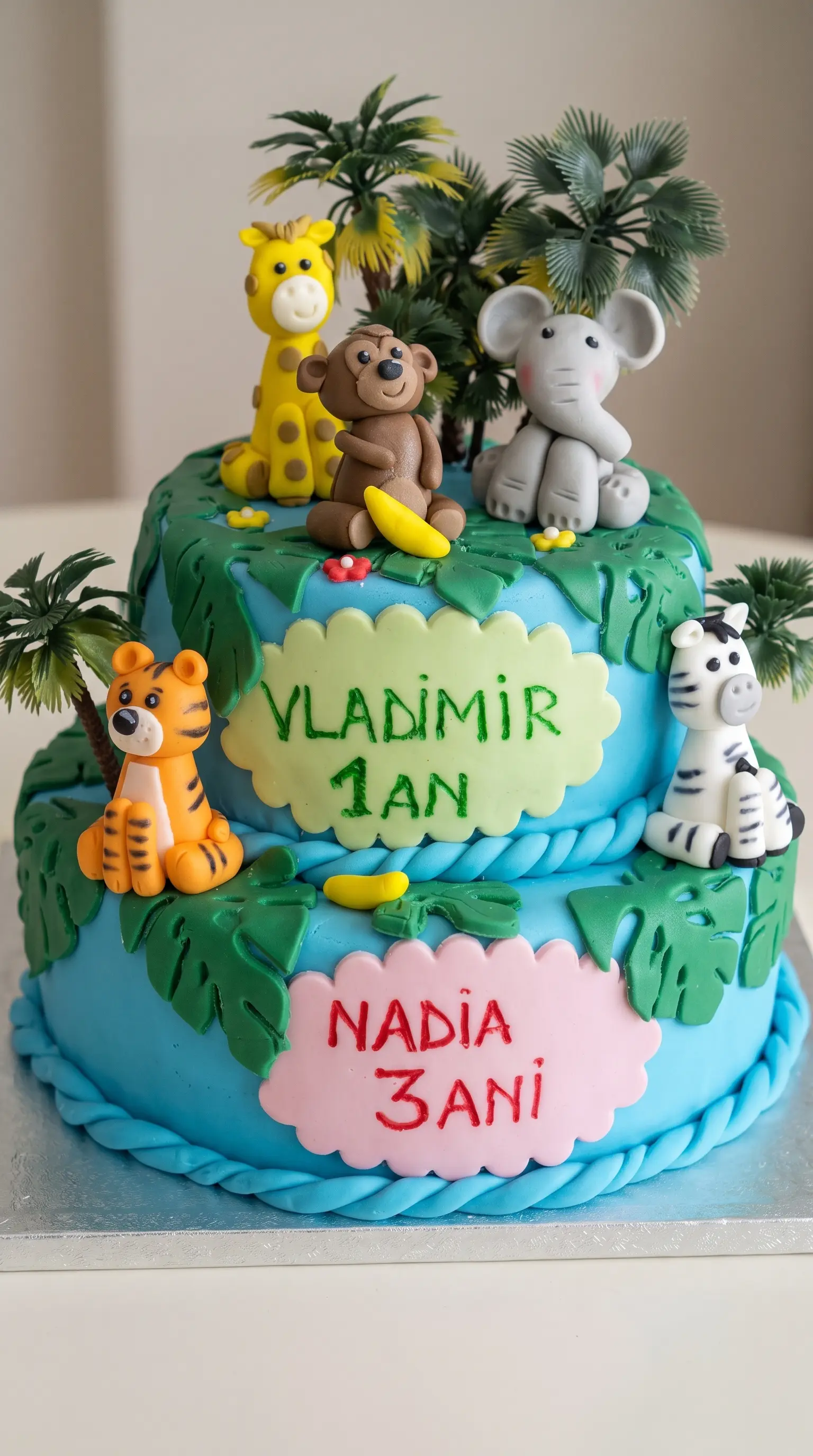 Two-tier children’s celebration cake decorated with jungle animals, tropical leaves and playful fondant details